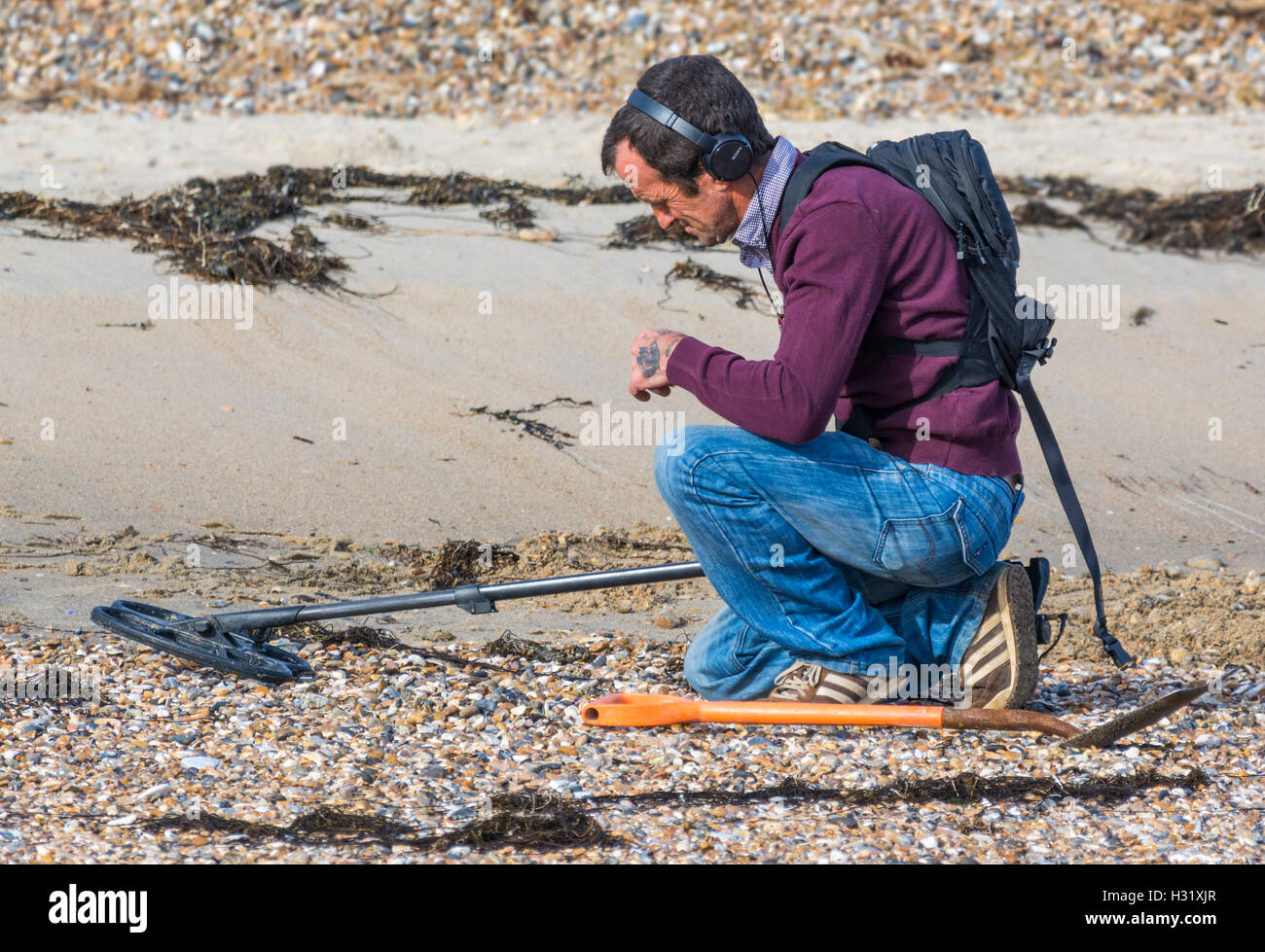 Mann auf der Suche nach einem Schatz mit einem Metalldetektor am Strand. Stockfoto