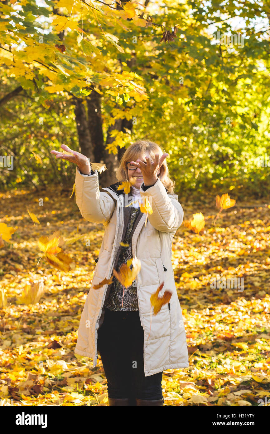 Porträt von Reife attraktive Frau spielt mit Herbst Stockfoto