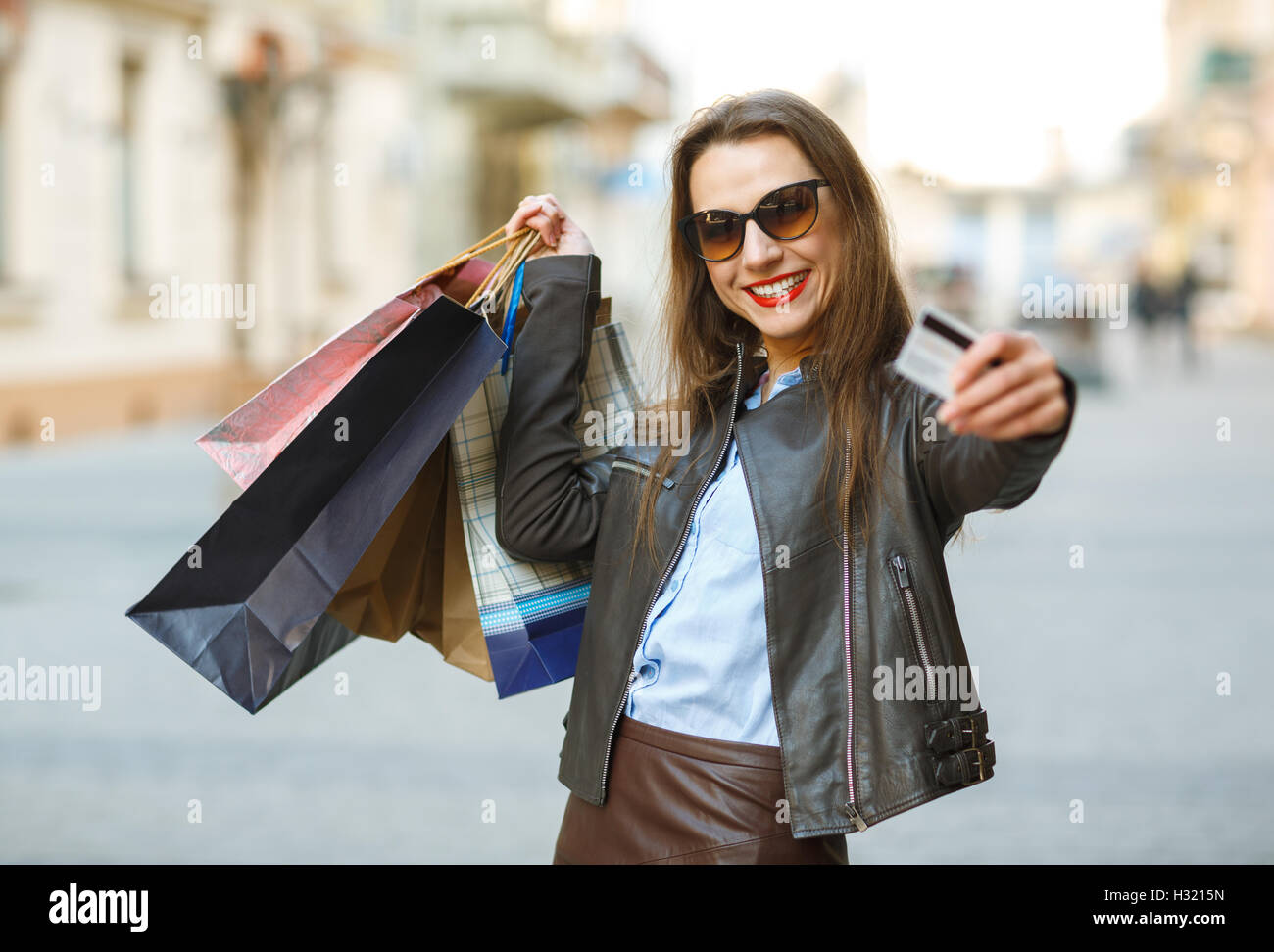 Verkauf, Einkauf, Tourismus und glückliche Menschen Konzept - schöne Frau mit Einkaufstüten und Kreditkarte in den Händen auf einer Straße Stockfoto