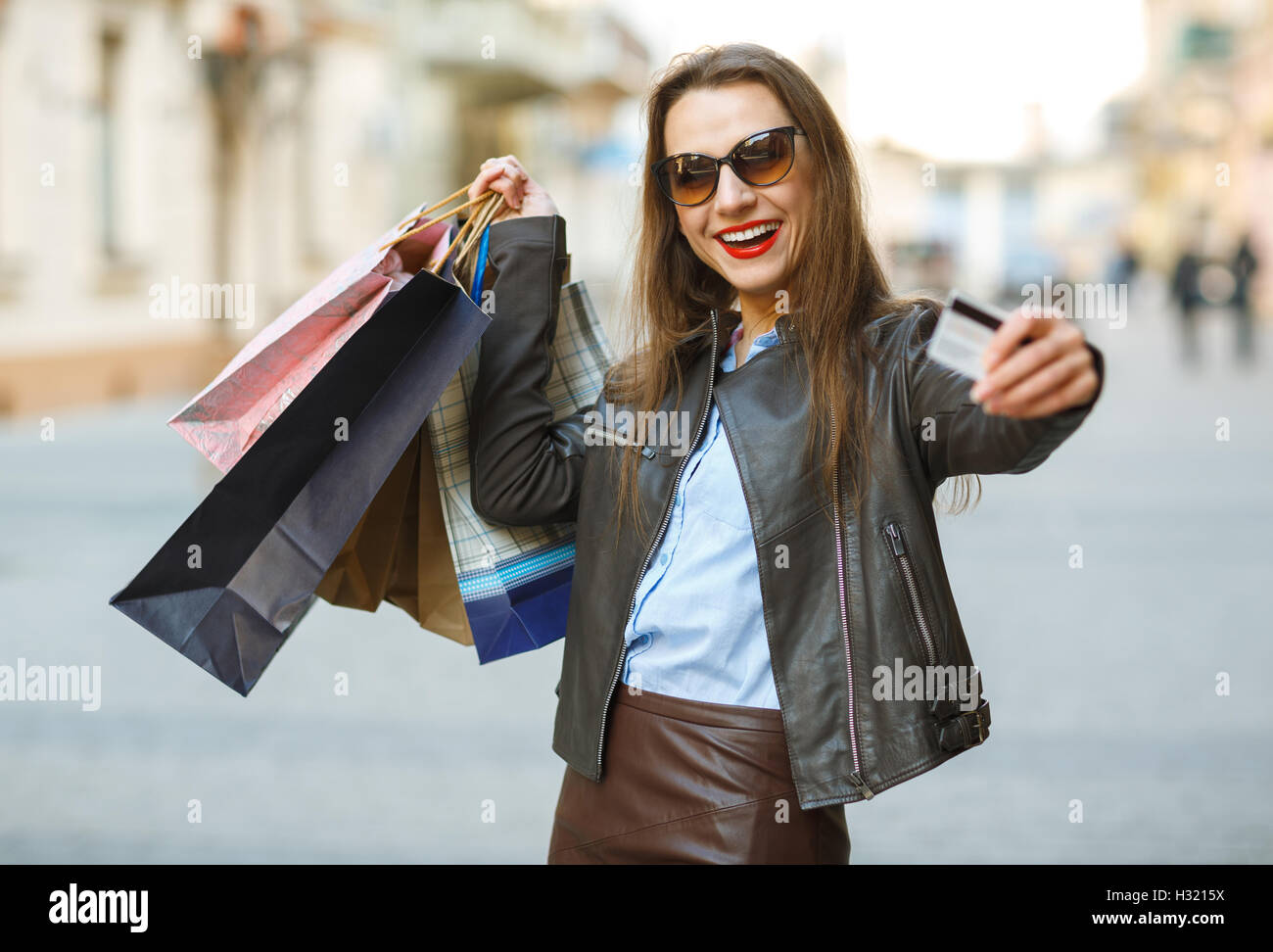 Verkauf, Einkauf, Tourismus und glückliche Menschen Konzept - schöne Frau mit Einkaufstüten und Kreditkarte in den Händen auf einer Straße Stockfoto