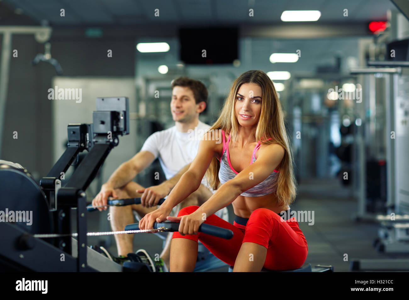 Sportliche paar - Mann und Frau, die Schulung an Zeile Maschine im Fitness-Studio Stockfoto