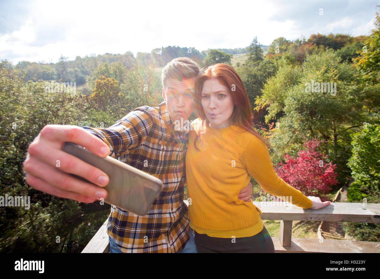 Junges Paar unter einem albernen Selfie auf ihrem Garten Balkon mit einem Smartphone. Stockfoto
