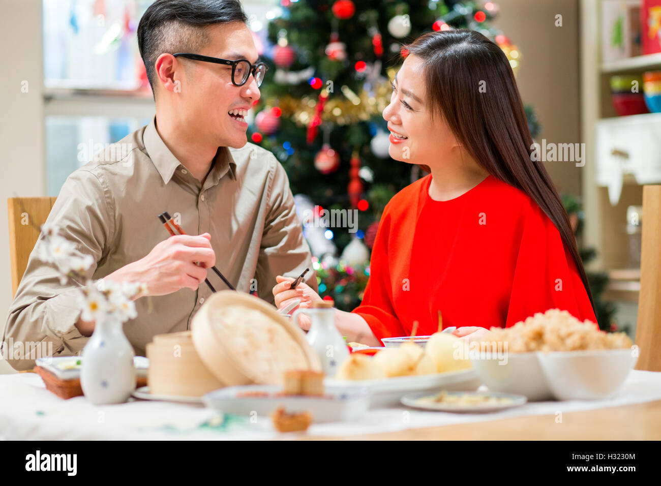 Chinesisches Ehepaar Weihnachtsessen gemeinsam genießen. Sie sitzen am Esstisch, mit Stäbchen um zu essen, chinesisches Essen. Stockfoto