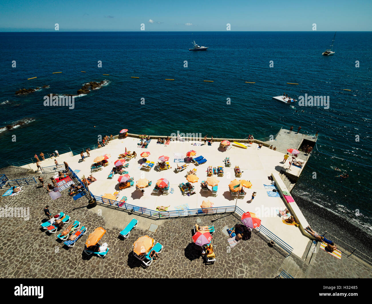 Menschen genießen das sommerliche Wetter auf einer künstlich angelegten Strand Plattform Funchal auf der portugiesischen Insel Madeira. Stockfoto