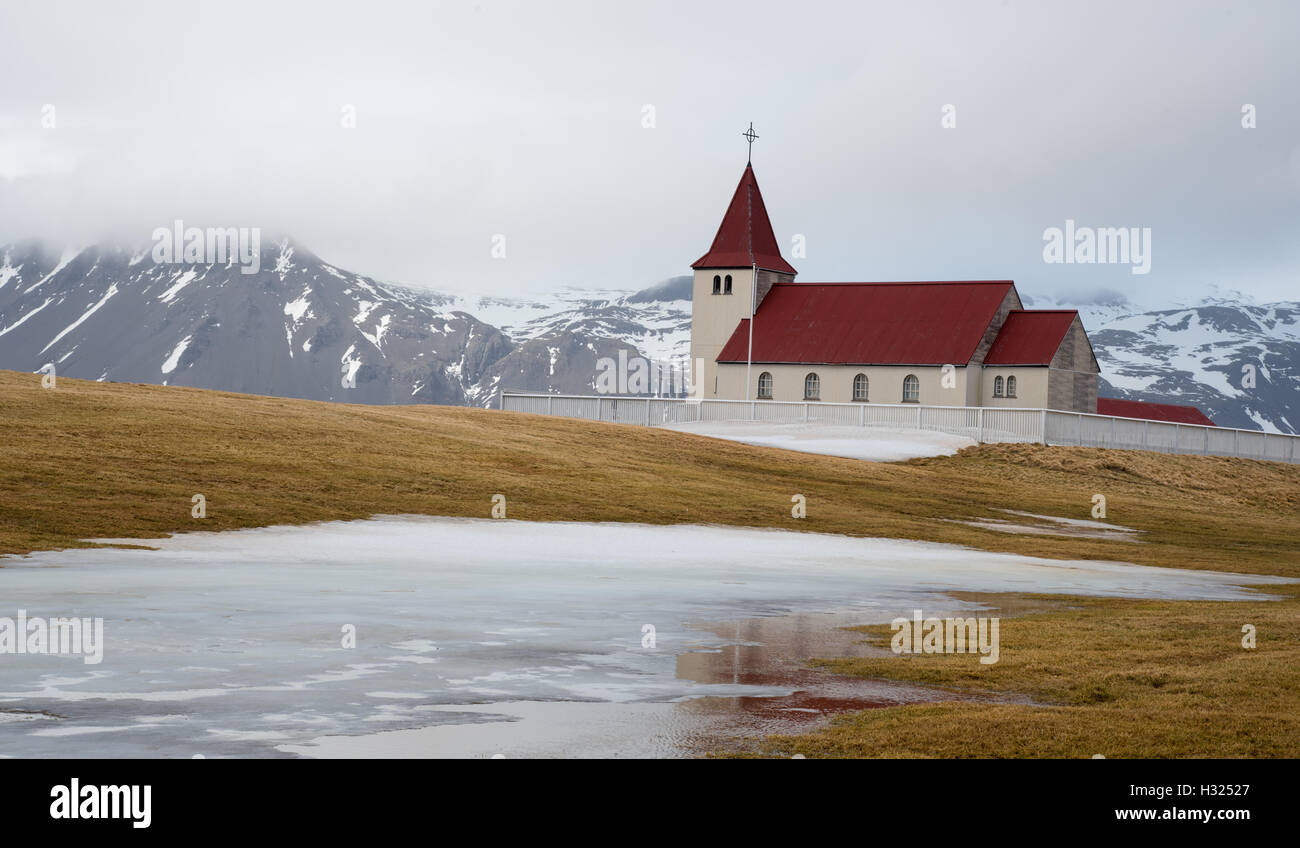 Traditionelle isländische Kirche mit rotem Dach reflektiert auf einem zugefrorenen See auf der Halbinsel Snæfellsnes auf Island Stockfoto