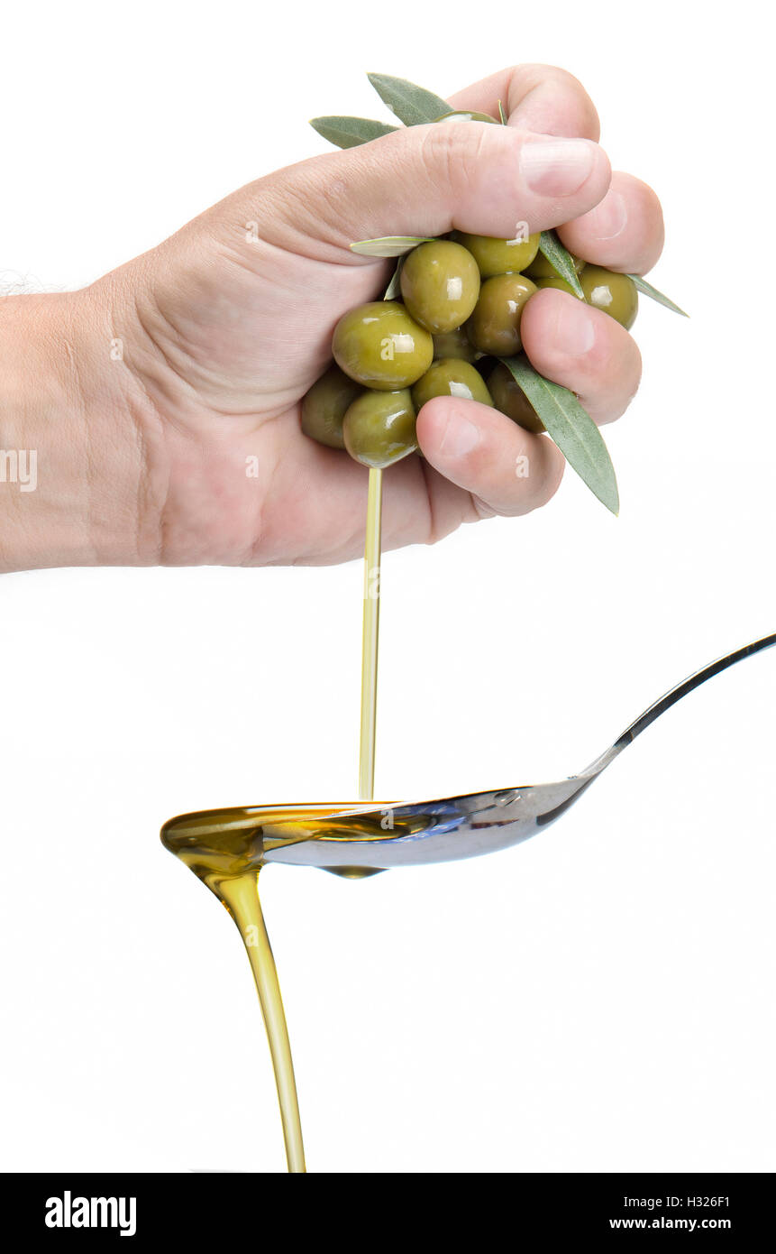 Eine Hand drückte Oliven und einen Löffel Olivenöl einsteigen. Stockfoto