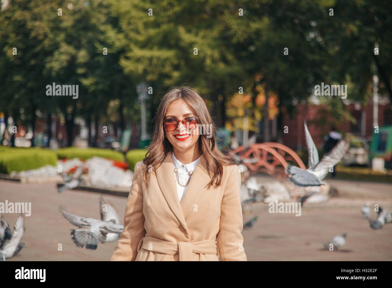 Mädchen mit Tauben in Sonnenbrille auf einer Stadt-Gasse Stockfoto