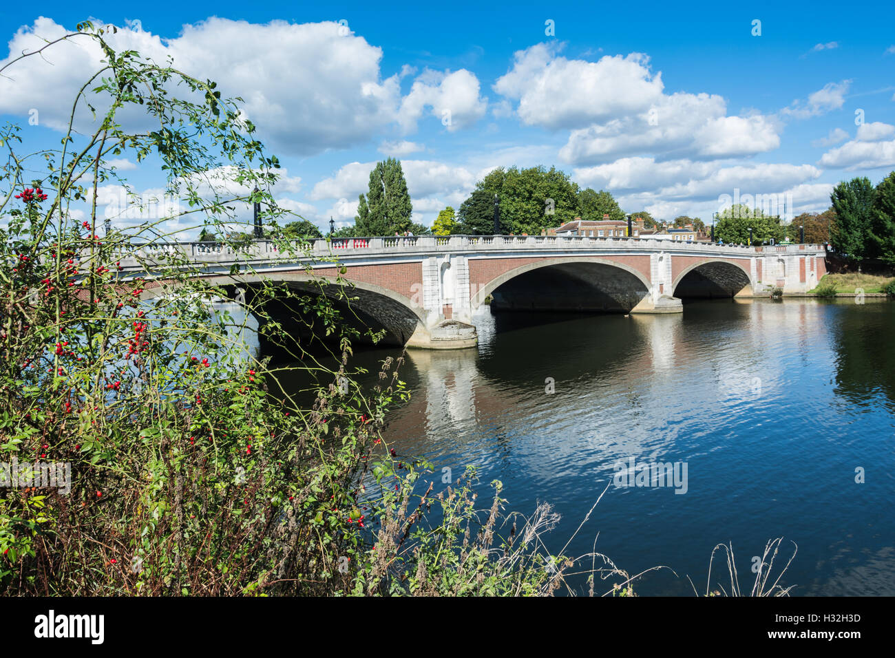 Eine ruhige Themse an der Hampton Court Bridge gegenüber dem Hampton Court Palace in Surrey, Großbritannien Stockfoto