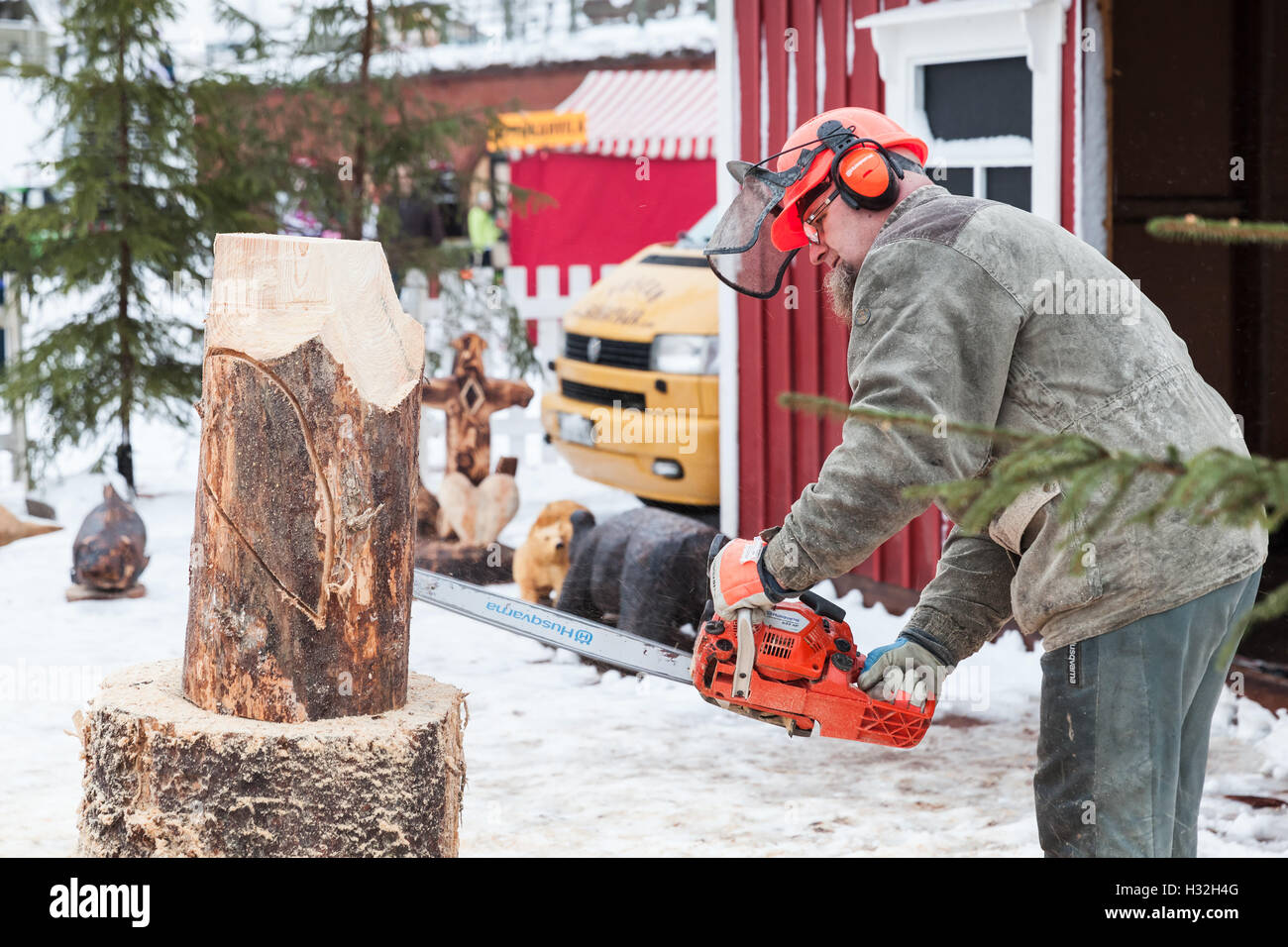 Hamina, Finnland - 13. Dezember 2014: Finnische Bildhauermeister mit einer Kettensäge produziert grobe Holzskulptur Stockfoto