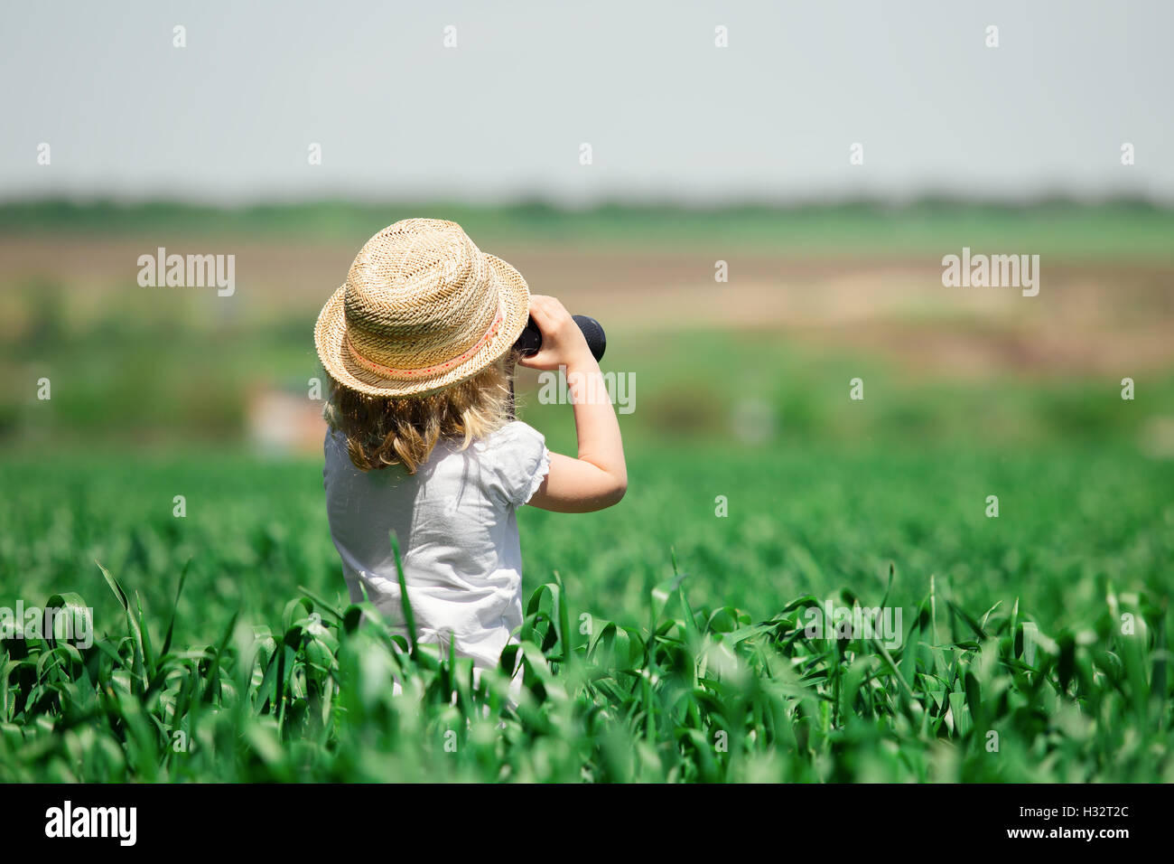 Kleines Mädchen im Feld Weg durch das Fernglas schauen Stockfoto
