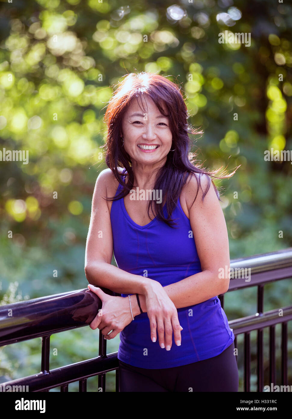 Asiatisch-amerikanische Frau, die an einen Zaun gelehnt Stockfoto