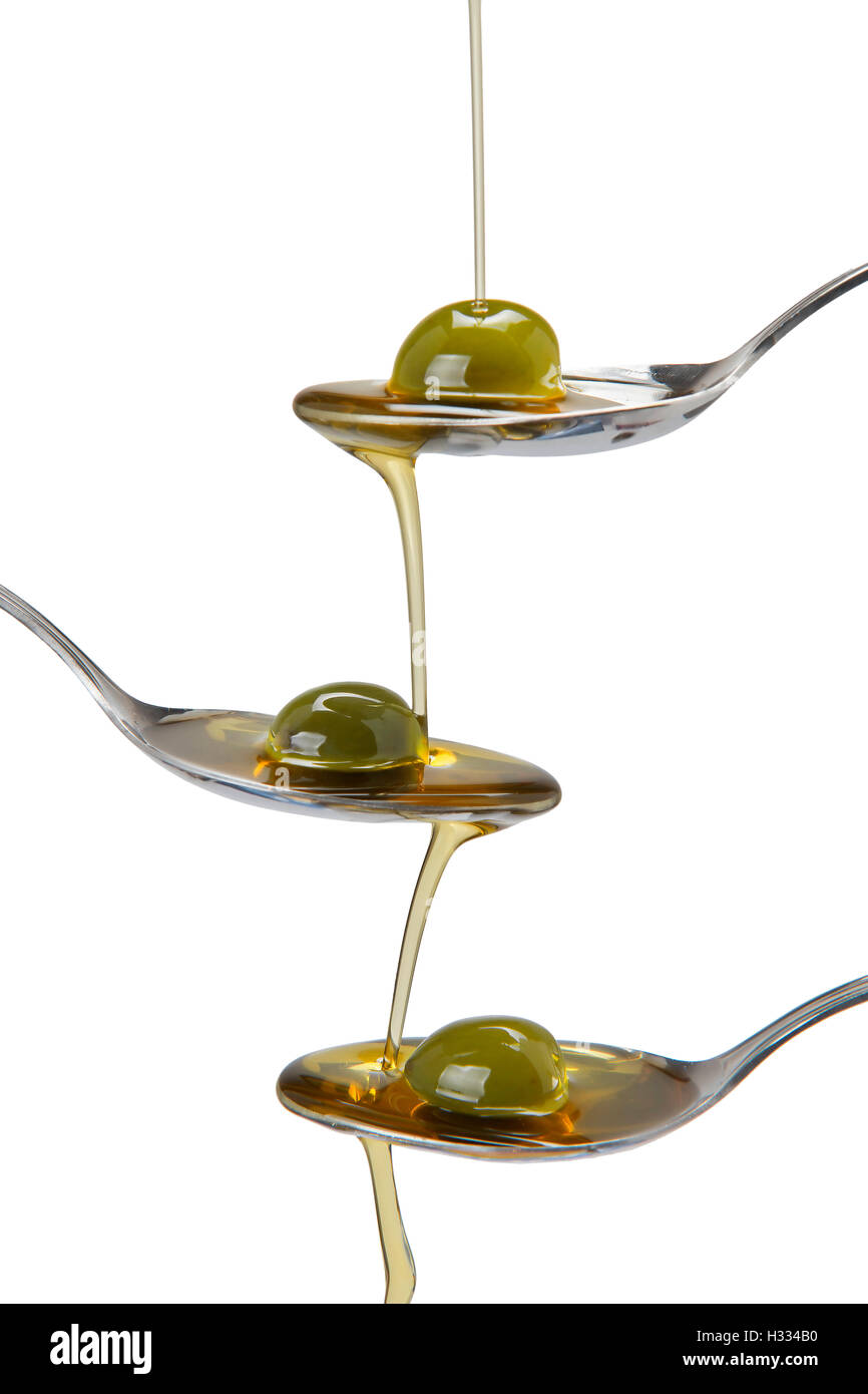 Olivenöl in einem Löffel gegossen und von einem zum anderen Löffel fallen Stockfoto