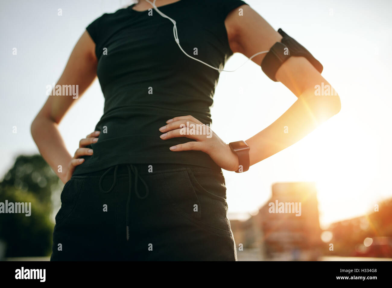 Schuss von Fit junge Frau mit ihren Händen auf den Hüften beschnitten. Urban Runner im Freien in sonnigen Morgen. Stockfoto