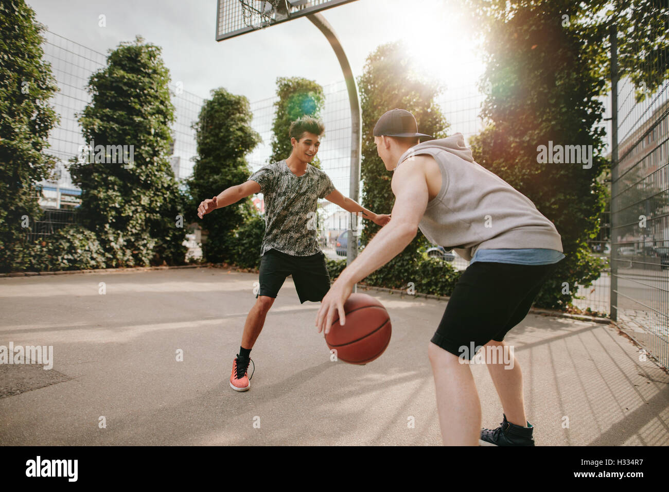 Junge Freunde zusammen zu spielen Basketball, junge vor Netto blockieren und andere dribbling den Ball auf Freiplatz. Stockfoto