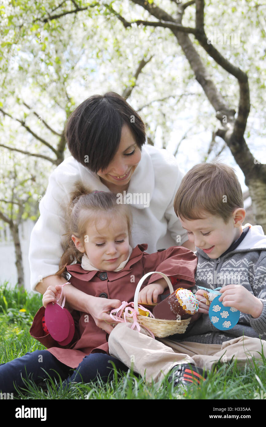 Mutter und zwei Kindern in blühenden Garten mit Ostern Dekor ele Stockfoto