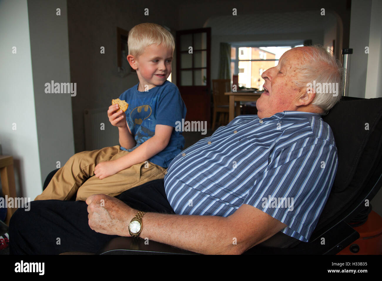 83 Jahre alte Großvater Interaktion mit seinen beiden jungen Enkel (im Alter von 3 und 6 Jahre alt) zu Hause in Hampshire, England, UK Stockfoto