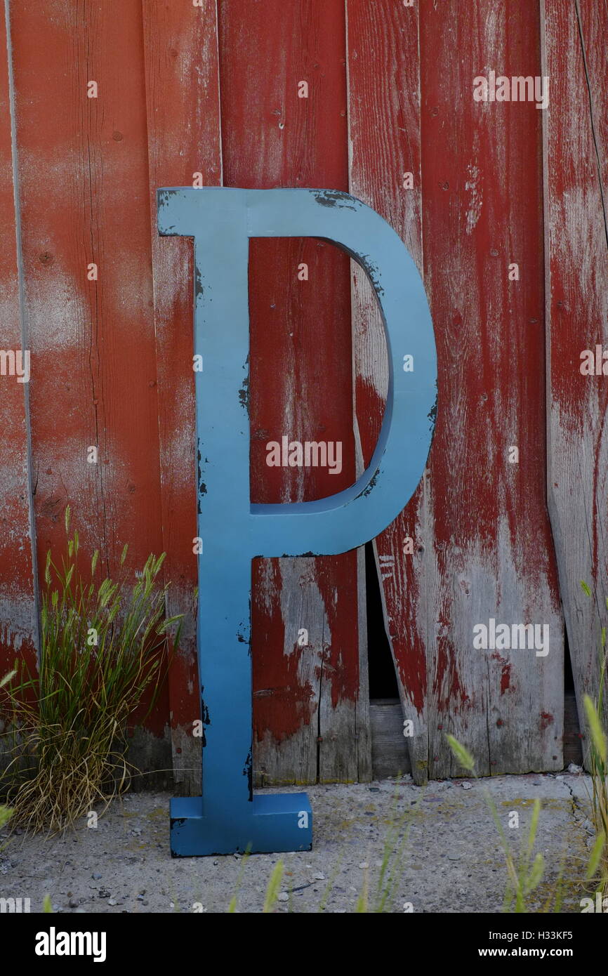 Blauer Brief P an alte rote Scheune Holz Wand Stockfoto