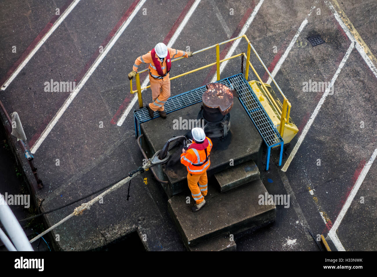 Hafenarbeiter anbringen vertäut Schiffs Trosse Shoreside Bitt im Seehafen dock Stockfoto