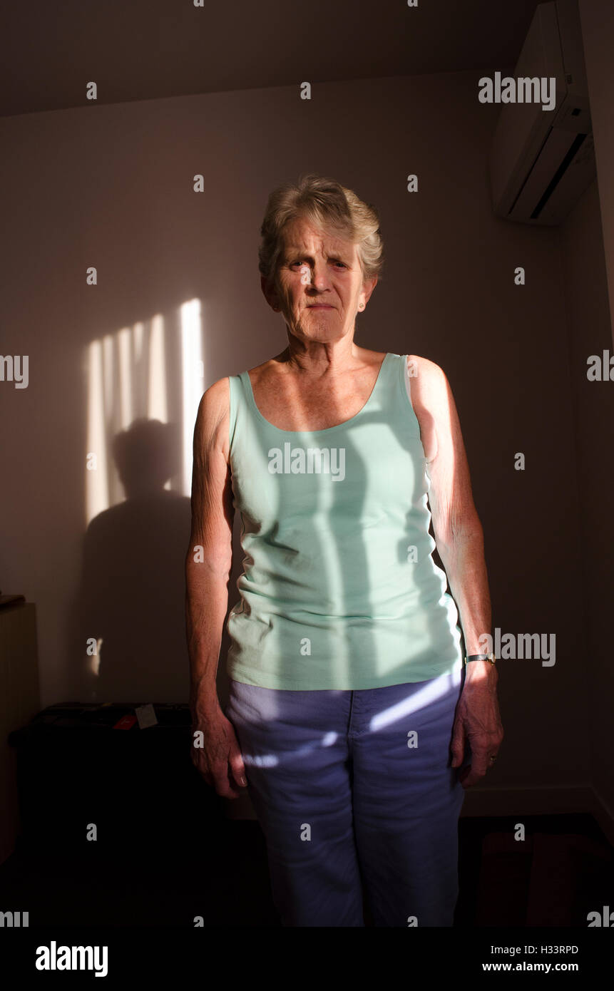 Portrait einer älteren Frau, die im Schatten eines Fensters blind Stockfoto
