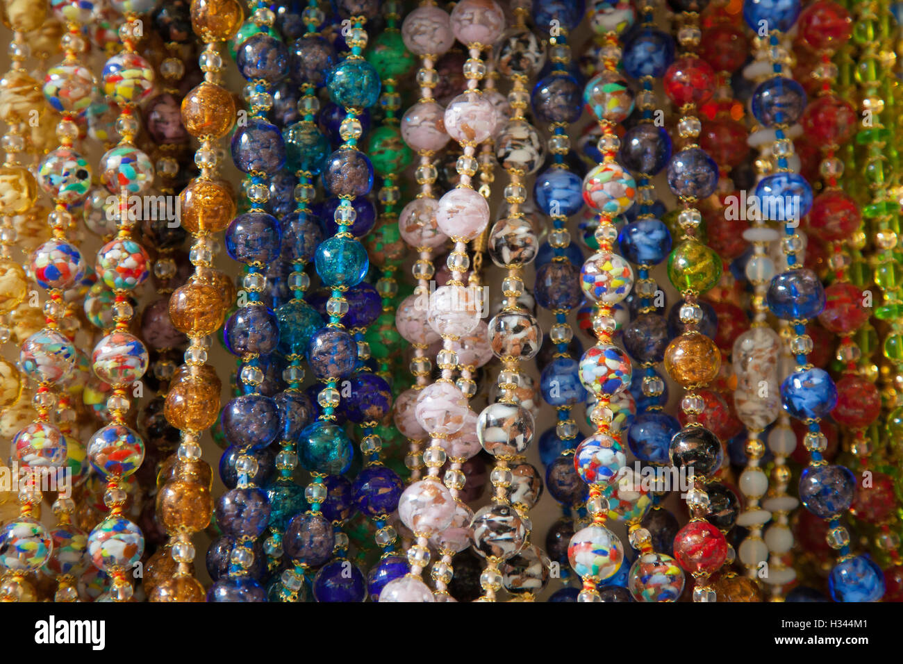 Saiten aus bunten Glasperlen hängen auf dem Display in einem Stall in den Straßen von Venedig. Stockfoto