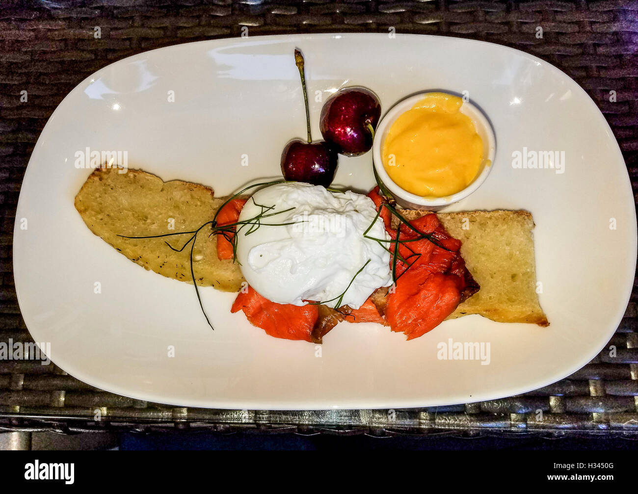 Lachs und Eiern Benedict Frühstück mit einer Seitenlänge von Kirschen. Stockfoto