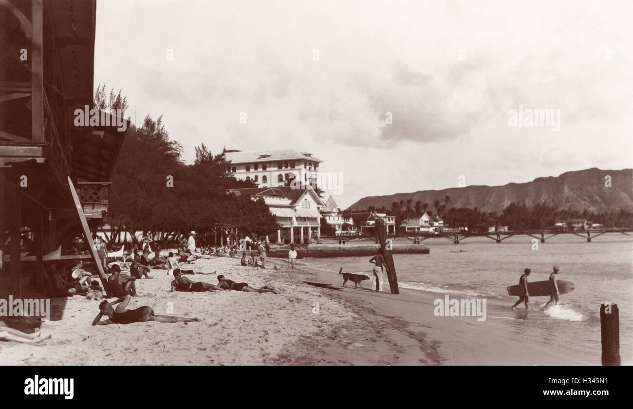 Waikiki-Strand-Szene mit Sonnenanbeter, Surfer und hölzernen Surfboards in Honolulu, Hawaii-Territorium c1920s. Stockfoto