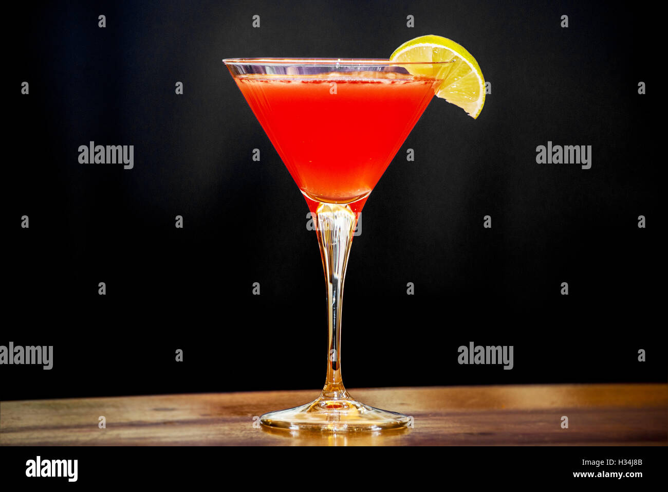 Mit einer Limettenscheibe Cosmopolitan Cocktail trinken Stockfoto