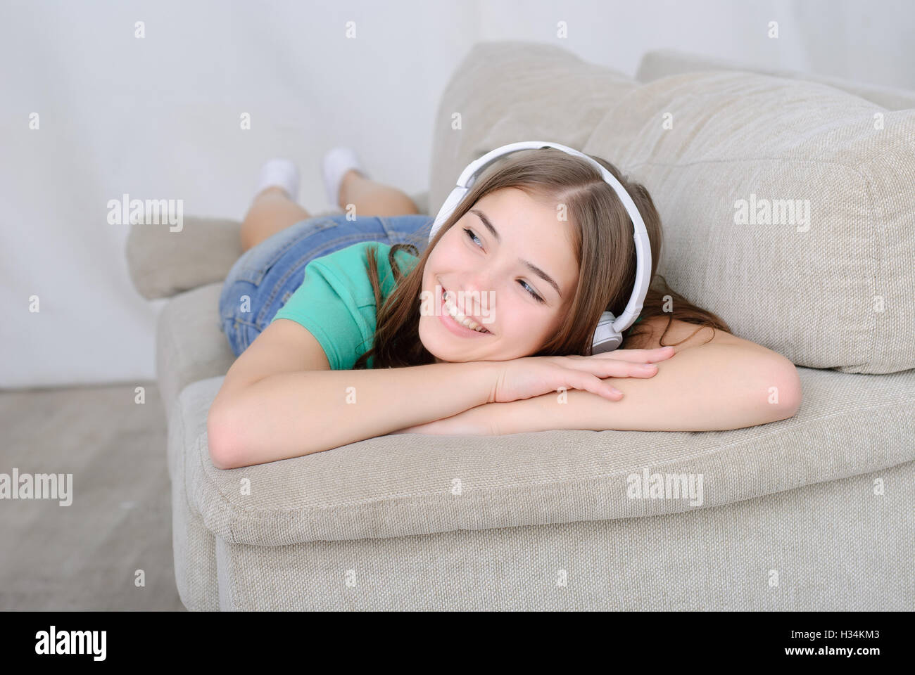 Frau Musik hören Kopfhörer sitzt auf dem Sofa im Zimmer Stockfoto