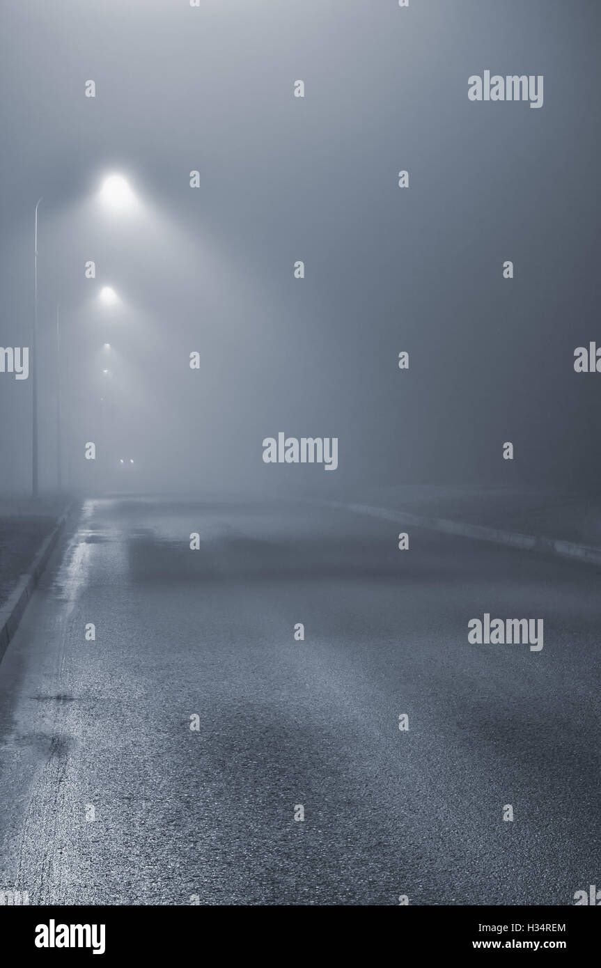 Straßenlaternen, nebligen Nacht und Nebel, Lamp Post Laternen, verlassenen Straße in Nebel Nebel, nassen Asphalt Asphalt, Autoscheinwerfer, nähert sich Stockfoto