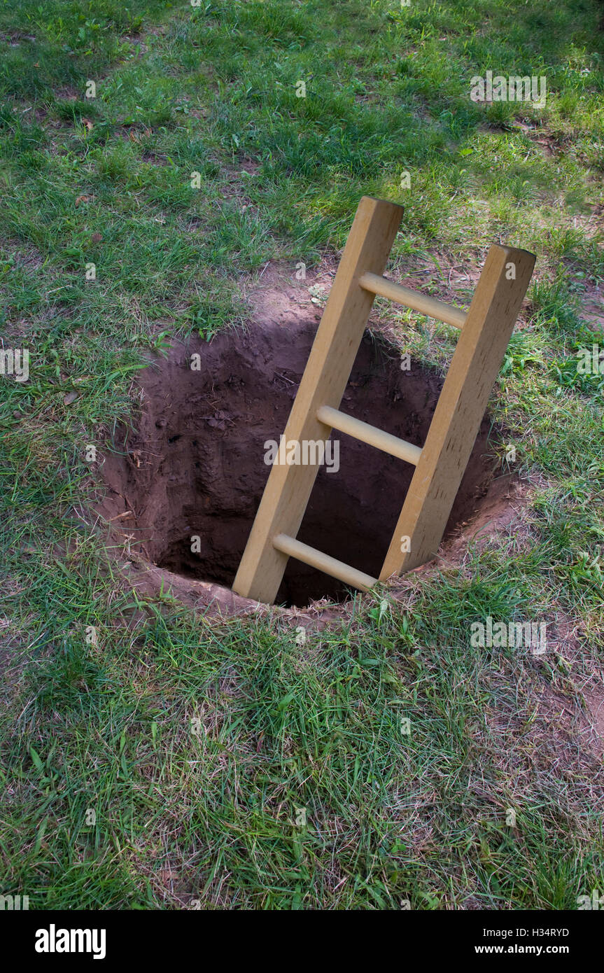 Leiter in tiefen Schmutz Loch im Boden oder Rasen Stockfoto