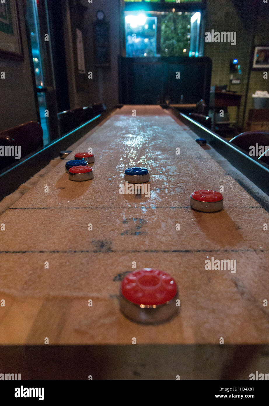 Shuffleboard Spiel Stehtisch mit Gewichten im Spiel in schummrigen Bar in den USA Stockfoto
