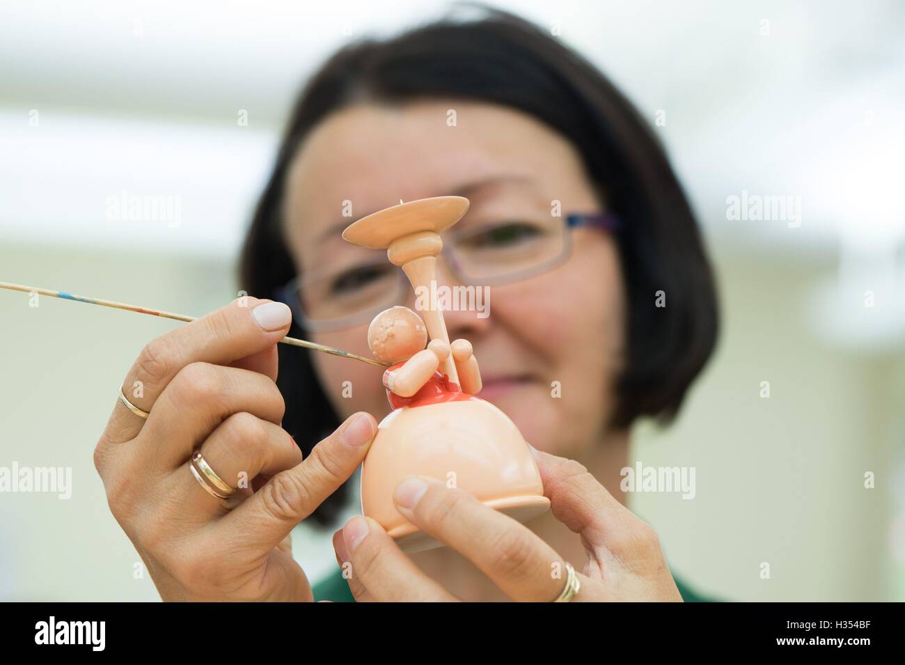 Figurenmaler Petra Wilde malt eine Engelsfigur, die eine Kerze in den Räumlichkeiten des Familienunternehmens Wendt & Kuehn in nhainichen, Deutschland, 20. September 2016 enthält. Das deutsche Unternehmen stellt handgefertigte kleine hölzerne Kunstwerke seit 1915 her. Seit 2014 wurden Figuren, hergestellt von der Firma auf dem Display in verschiedenen Städten wie St. Petersburg, Moskau und Shanghai im Rahmen einer Welttournee "Handmade in Germany." Die nächste Station wird Peking, China, vom 21. bis 30. Oktober 2016 sein. Foto: Sebastian Kahnert/dpa Stockfoto