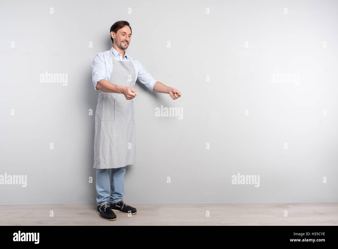 Erfreut Mann macht Kochen Geste auf einem grauen Hintergrund Stockfoto