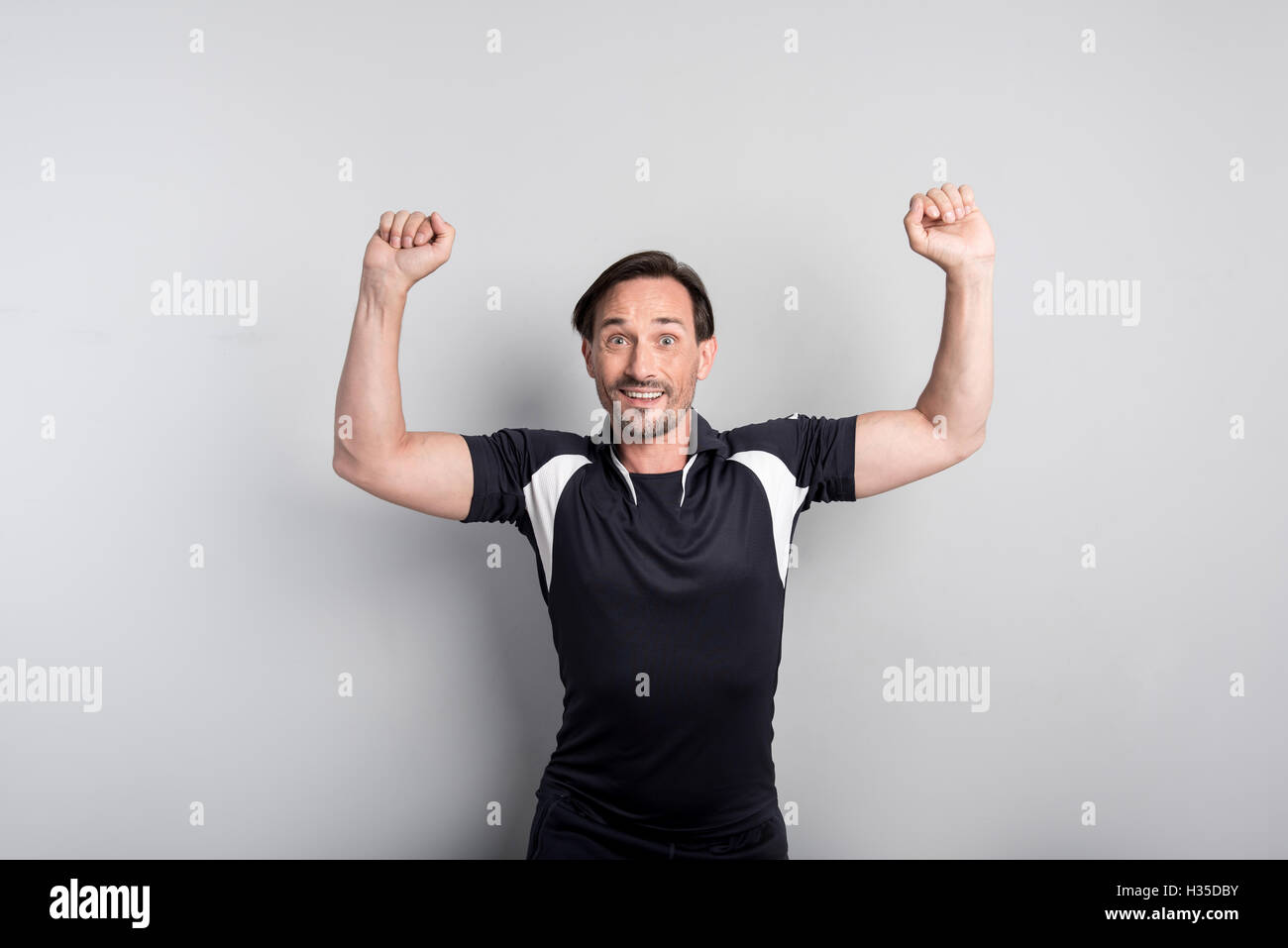 Freudige sportlicher Mann zeigt seine Muskeln Stockfoto