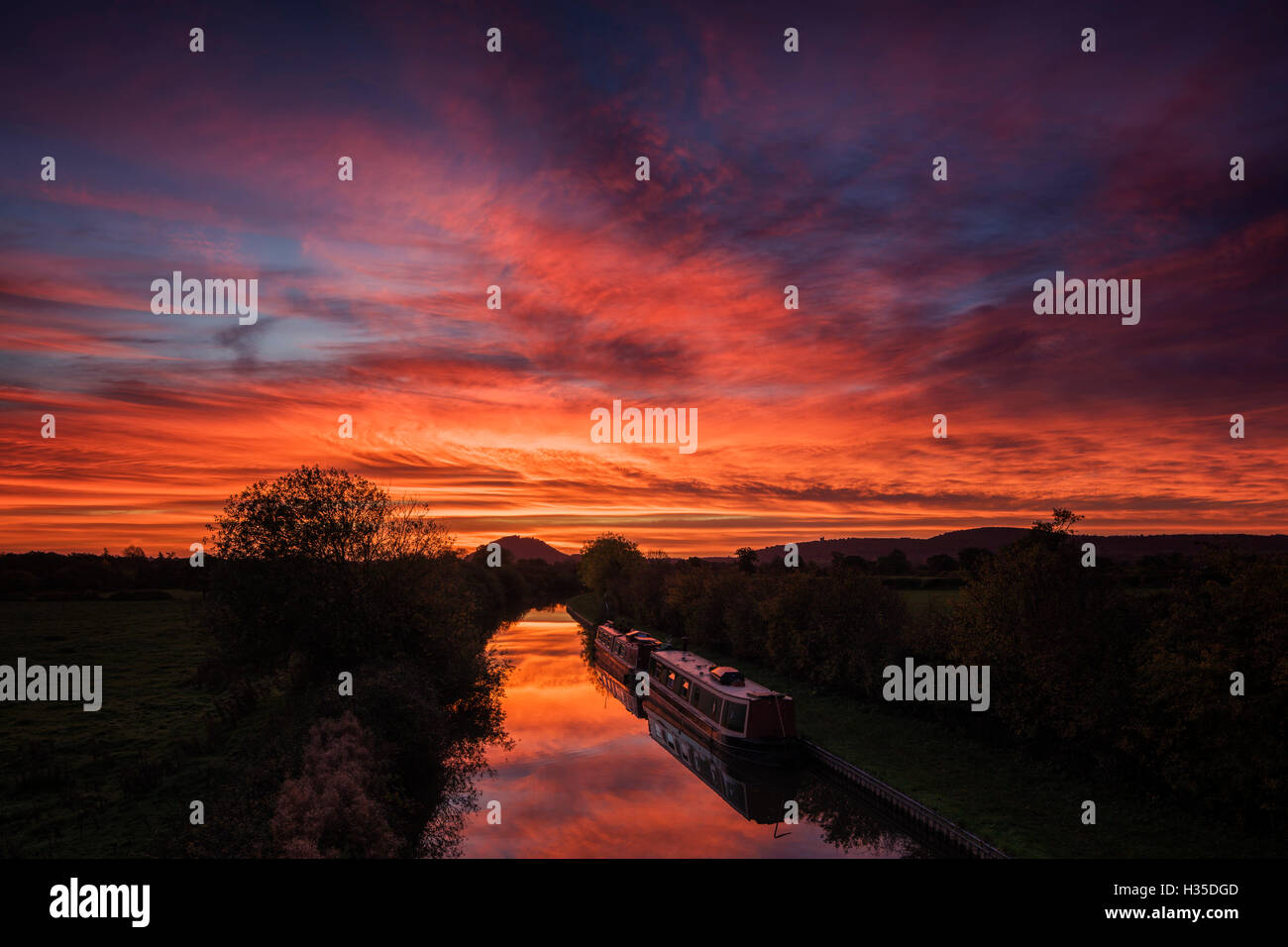 Lastkähne lag immer noch auf dem Shropshire Union Kanal wie die Morgenröte, die Licht über den Himmel über Beeston Burg, Cheshire, UK fegt Stockfoto