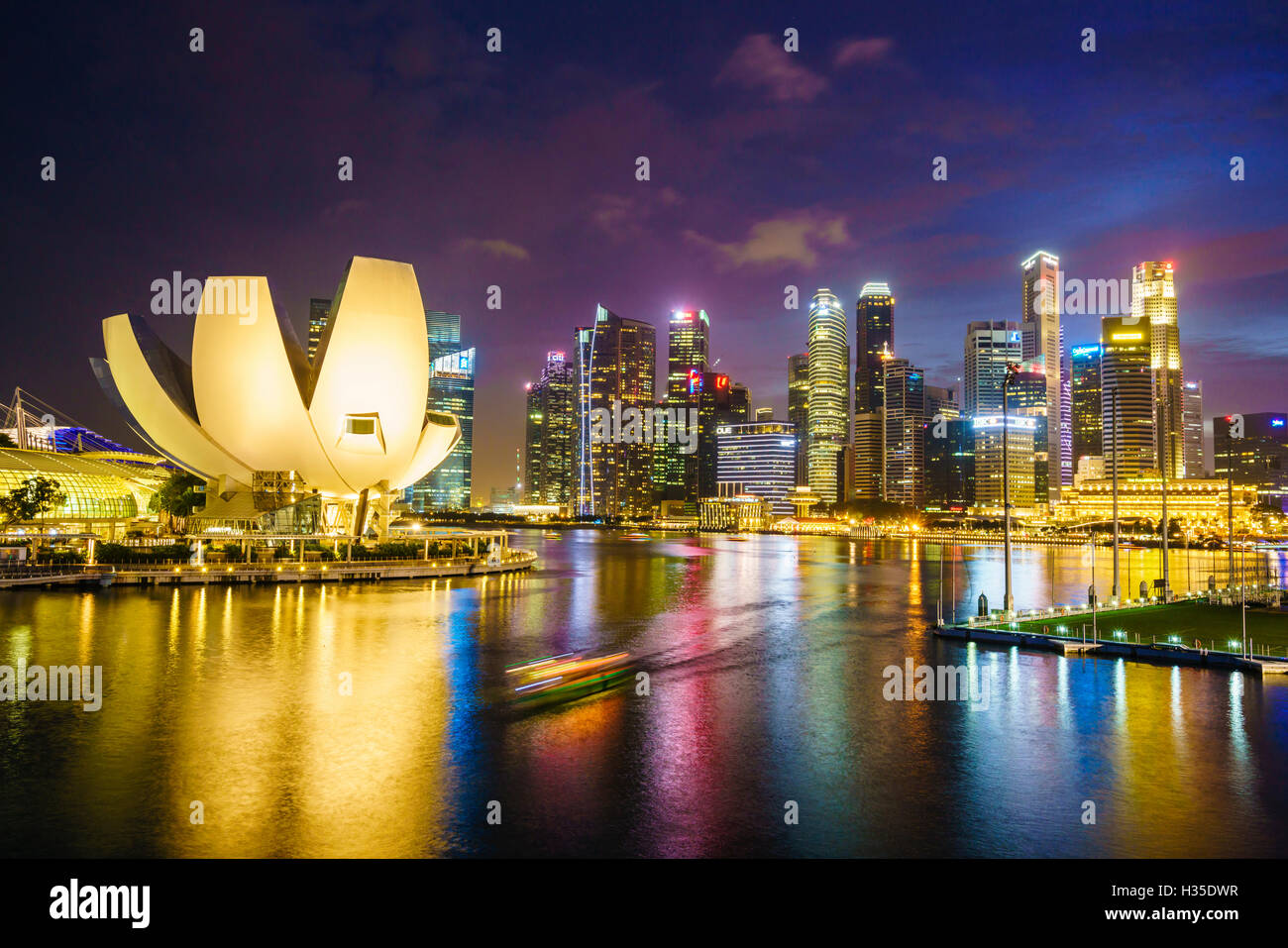 Der Lotus Blume geformt ArtScience Museum mit Blick auf Marina Bay mit der Skyline der Stadt darüber hinaus in der Nacht, Singapur beleuchtet Stockfoto