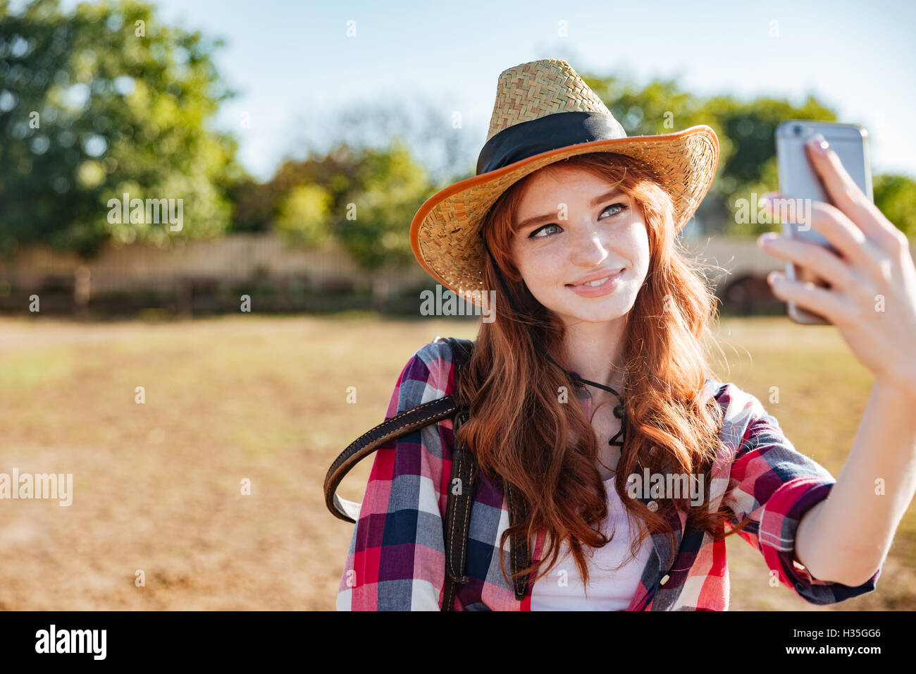 Lächelnd attraktive junge Frau Cowgirl Ranch Selfie mit Handy übernehmen Stockfoto
