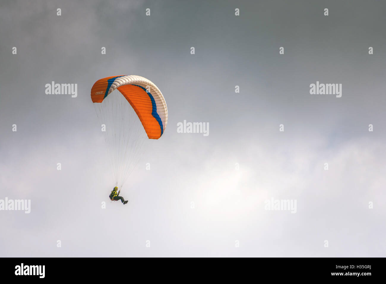 Solo-orange Gleitschirmspringen, Paragleiter, Hanglider fliegen, gegen grauen grauen Himmel Stockfoto