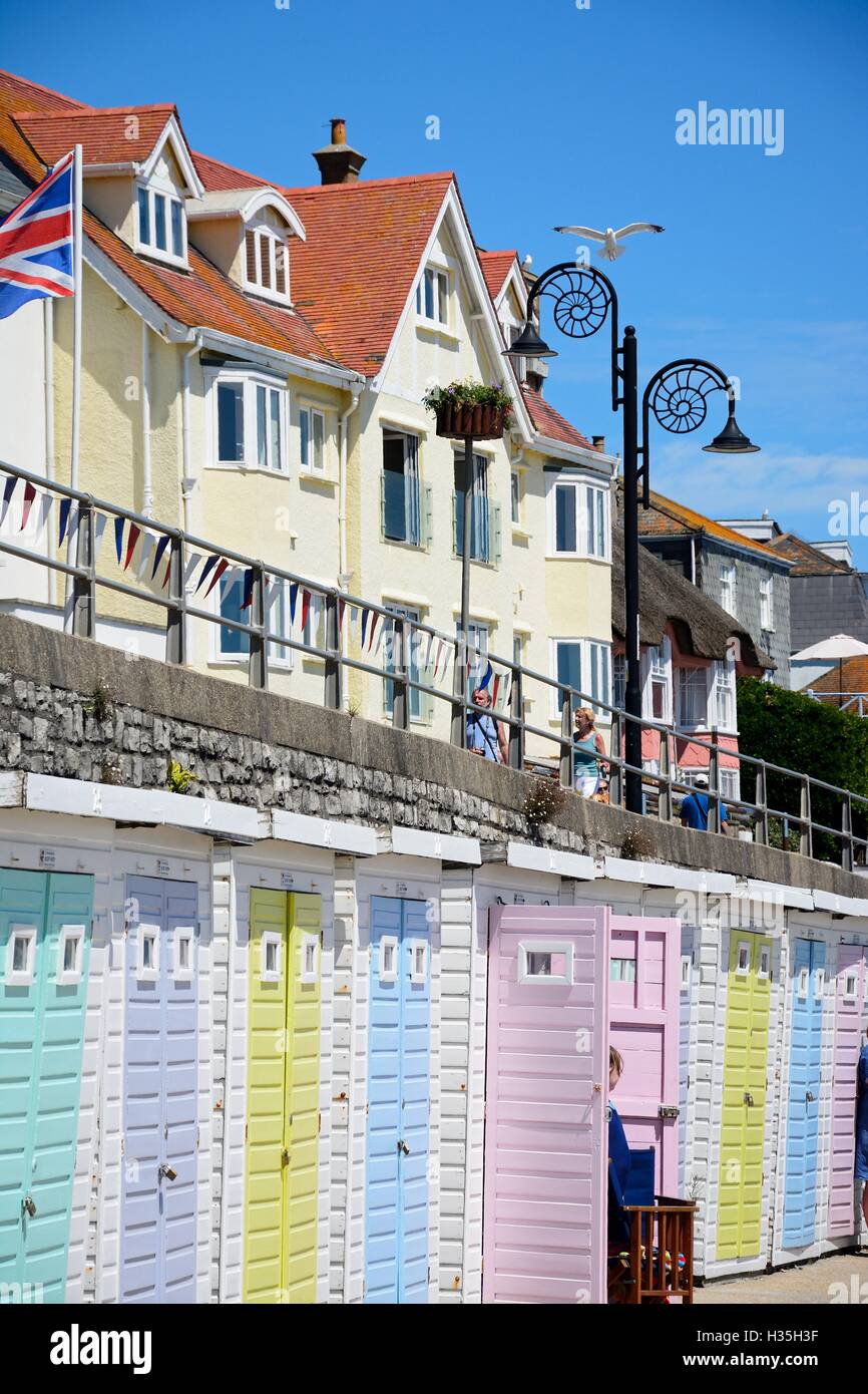 Reihe von bunten Strandhäuschen entlang der Kante des Strandes und der Promenade mit Touristen genießen die Einstellung, Lyme Regis, UK. Stockfoto