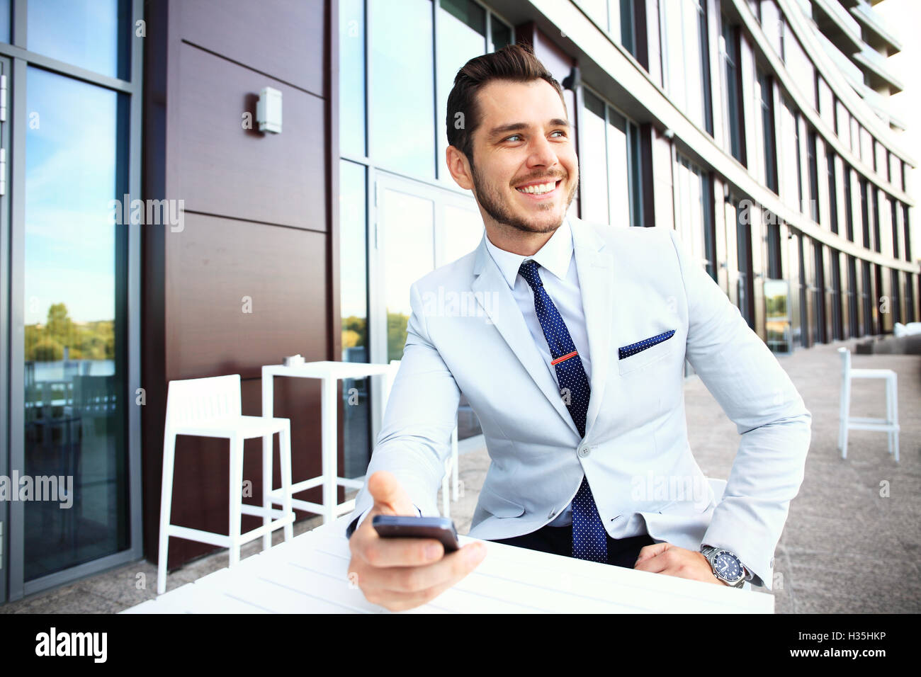 Gut aussehender Mann arbeiten mit Smartphone und Dokumenten im Café im freien Stockfoto