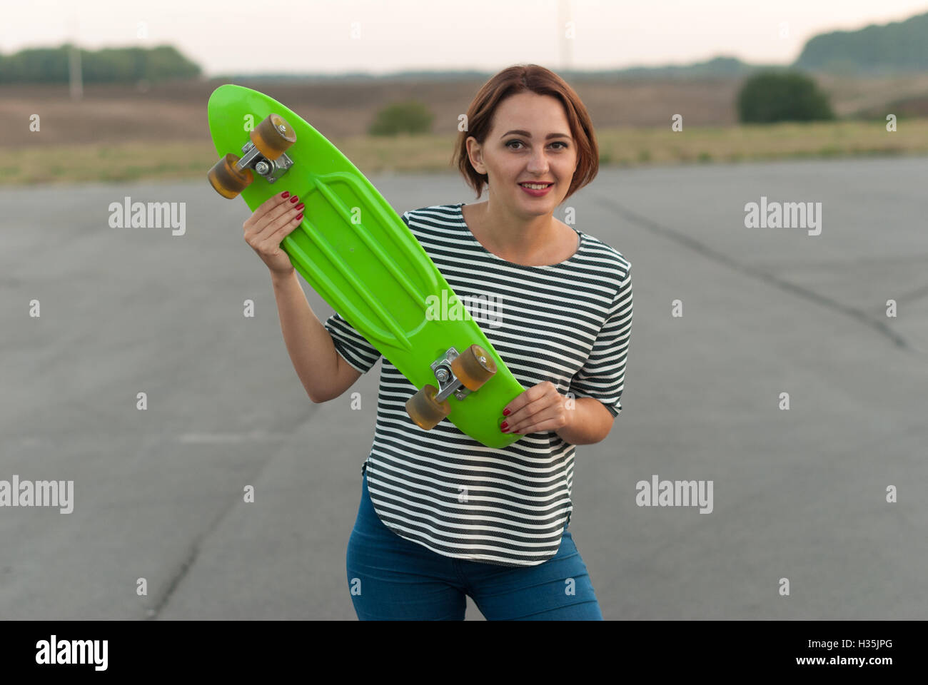 Fröhliches junges Mädchen mit einem Skateboard in Händen. Stockfoto