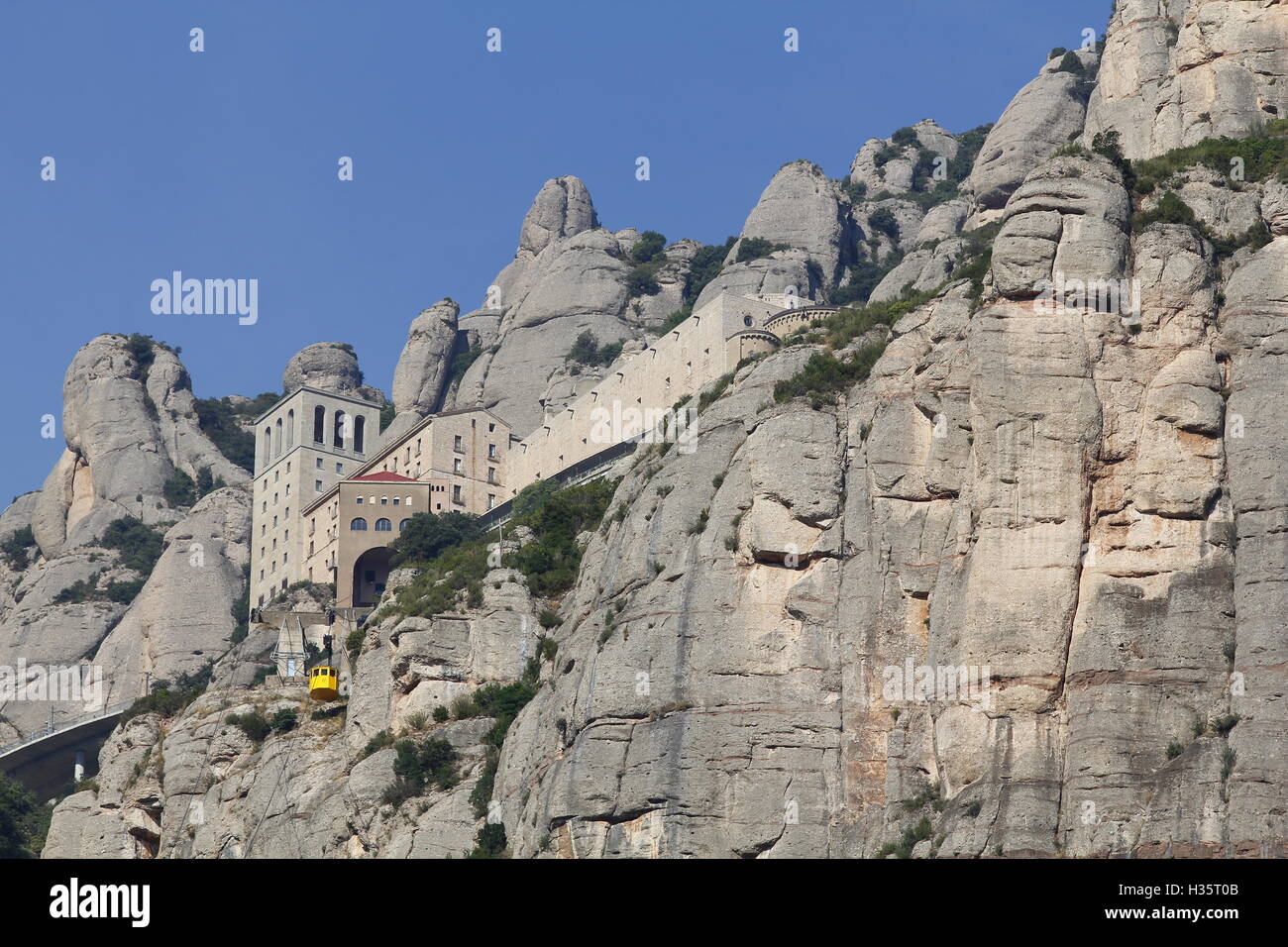 Abtei von Santa Maria de Montserrat in der Spitze des Berges mit der gelben Luftseilbahn Stockfoto