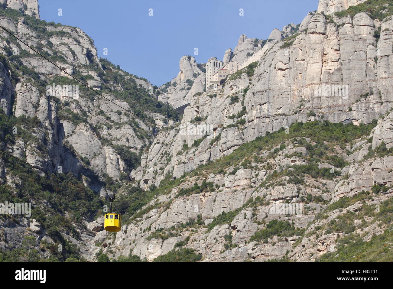 Abtei von Santa Maria de Montserrat in der Spitze des Berges mit der gelben Luftseilbahn Stockfoto