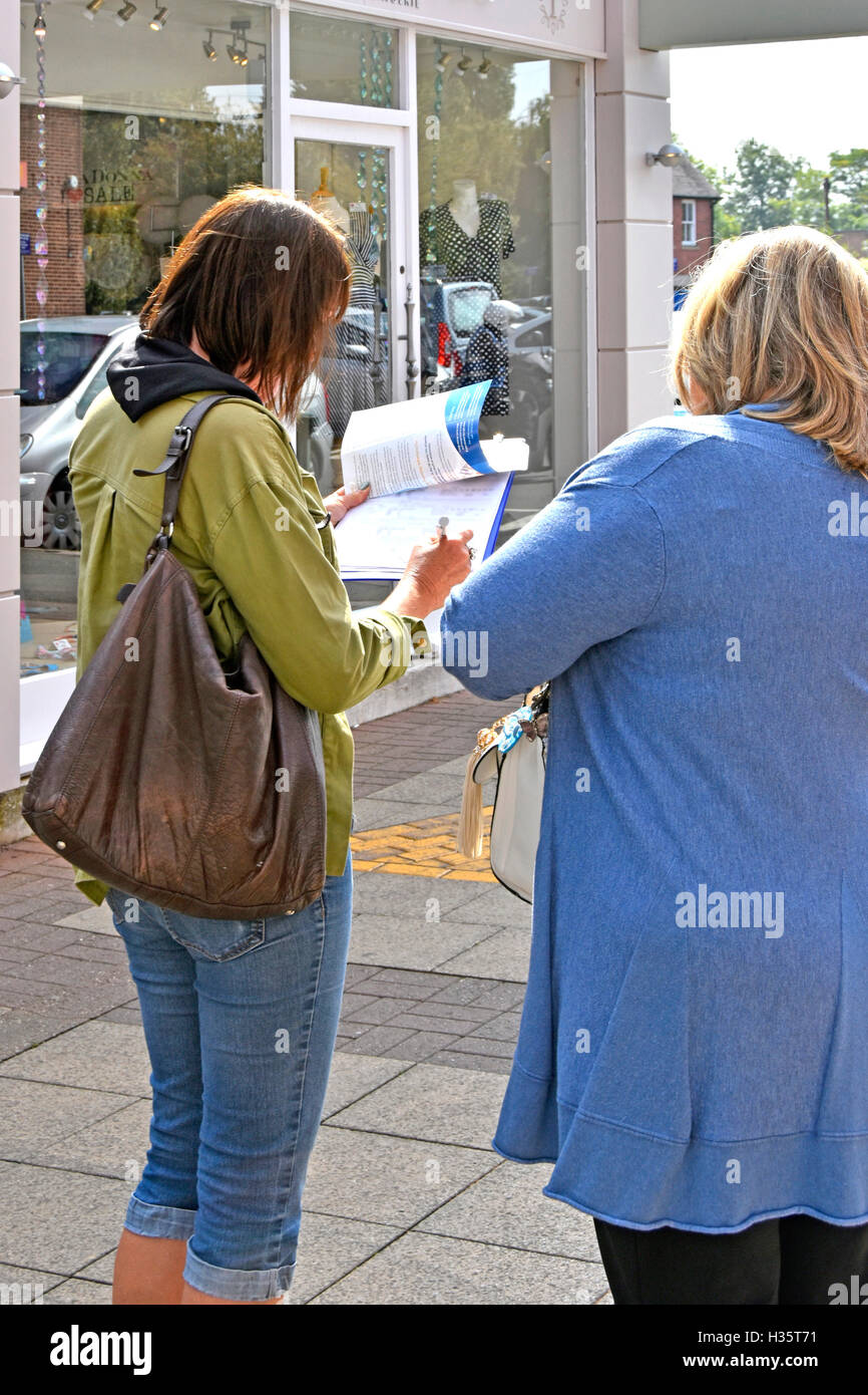Frau mit Klemmbrett (Daten verschwommen eingegeben) Interview Befragung Frau Käuferin kleine britische Innenstadt Straßenmarktforschung Umfrage Women Concept Stockfoto