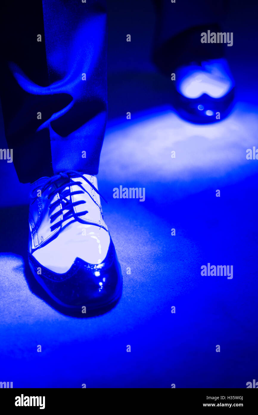 Latein und Salsa Tänzer im schwarzen und weißen Jazz Tanzschuhe in hellen und dunklen blau leuchtet auf der Bühne. Stockfoto