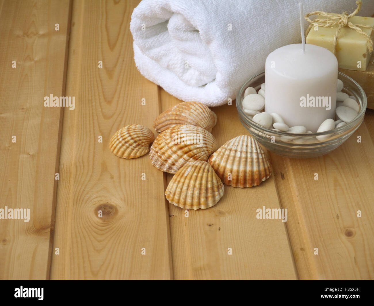 Handtuch, Seife, Kerzen und Muscheln auf dem hölzernen Hintergrund Stockfoto