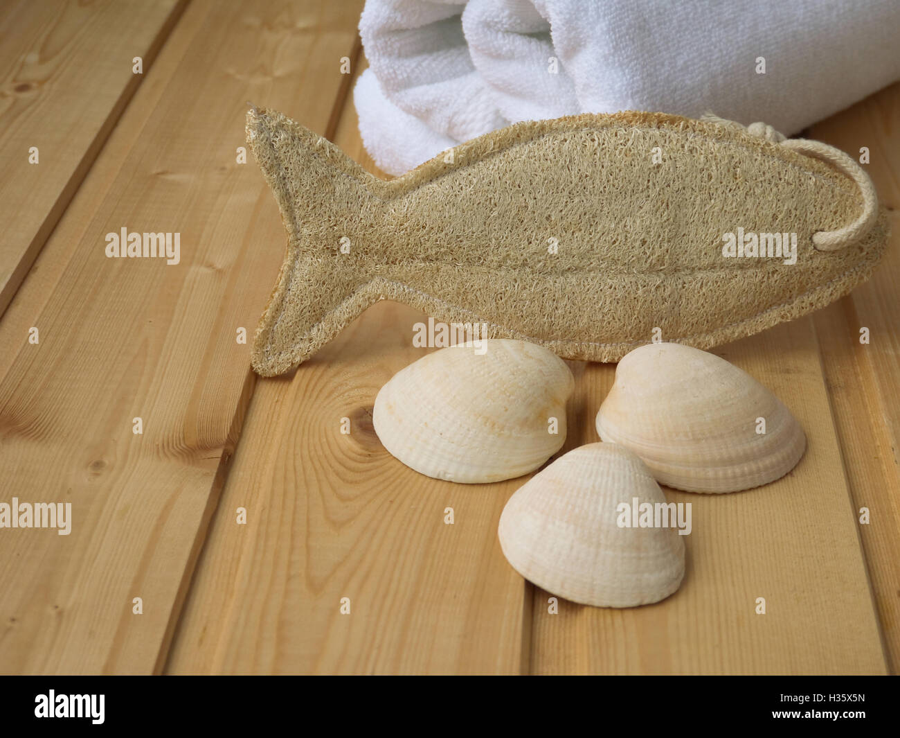 Handtuch, Muscheln und Luffa Wisp auf dem hölzernen Hintergrund Stockfoto