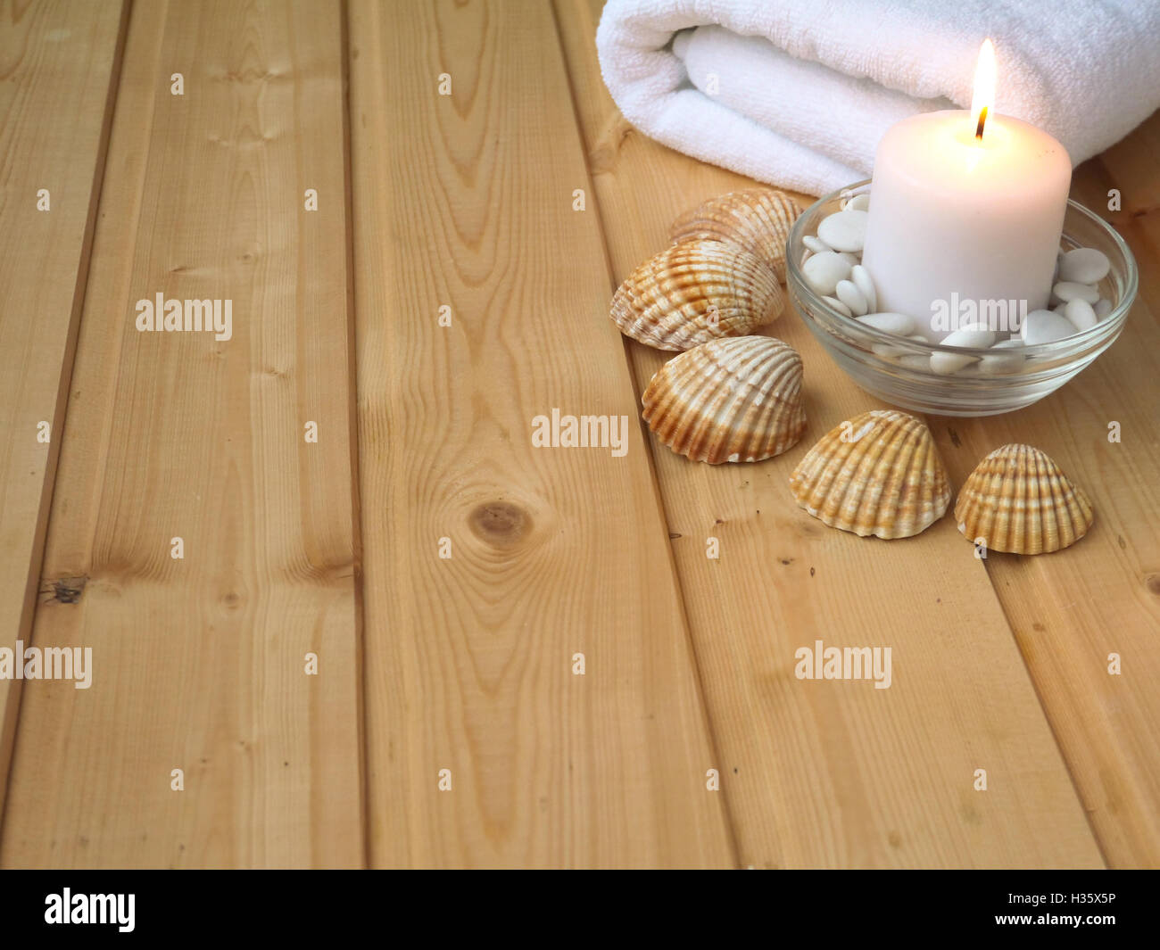 Handtuch, Muscheln und brennende Kerze auf dem hölzernen Hintergrund Stockfoto