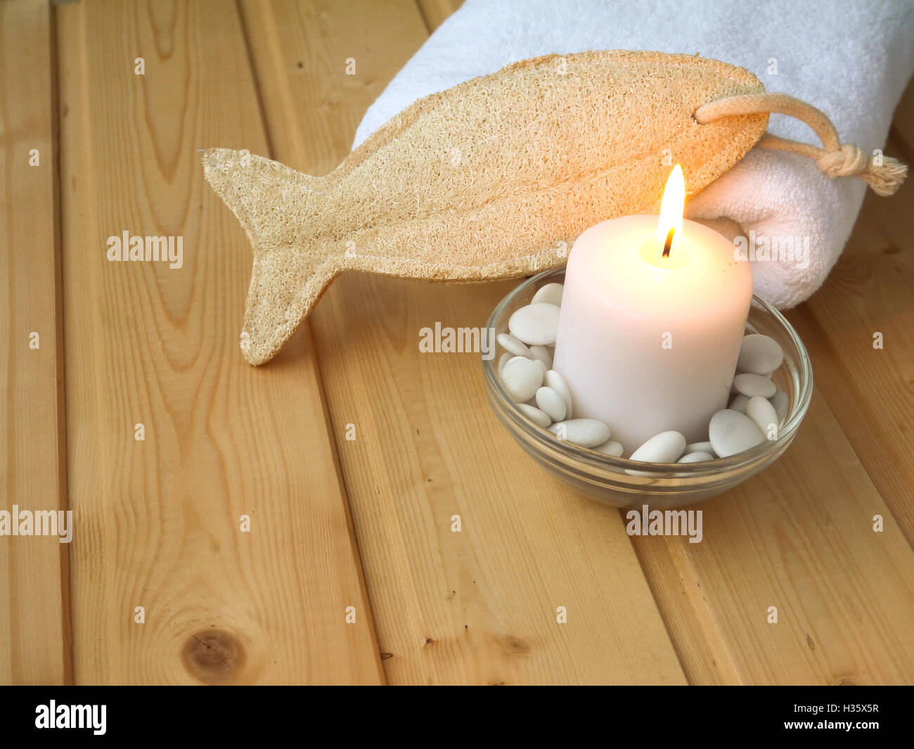 Handtuch, Luffa Wisp und brennende Kerze auf dem hölzernen Hintergrund Stockfoto
