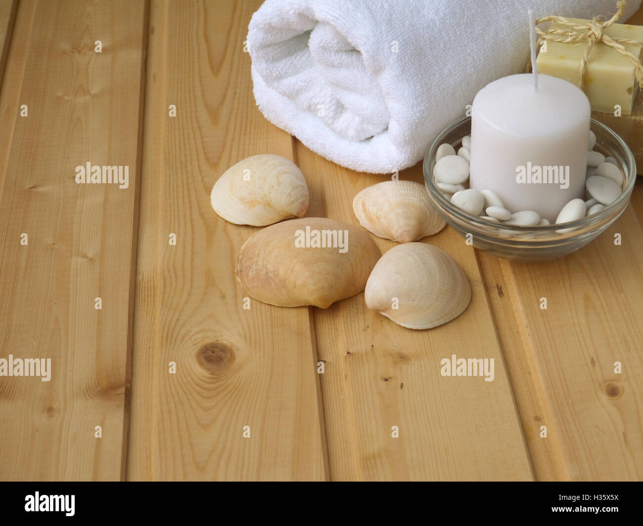 Handtuch, Seife, Kerzen und Muscheln auf dem hölzernen Hintergrund Stockfoto